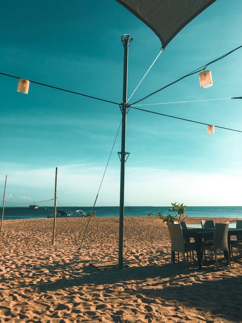 餐桌旁的三盏吊灯可观赏平静的海面和海滨 · 免费素材图片