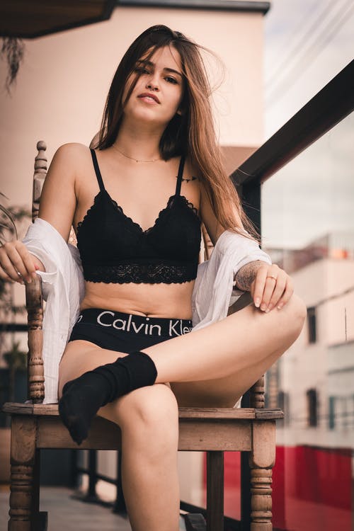 坐着女人穿着黑色calvin Klein Pantie交叉腿 · 免费素材图片