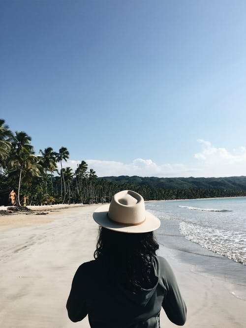 女人穿着灰色夹克在海边散步 · 免费素材图片