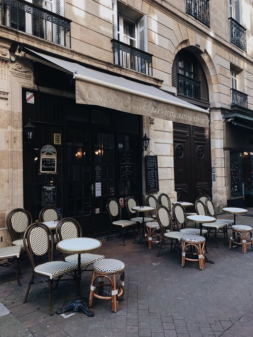 咖啡馆前面的白色和棕色木制餐桌椅 · 免费素材图片