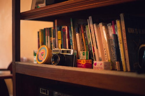 黑色复古相机在书架上 · 免费素材图片