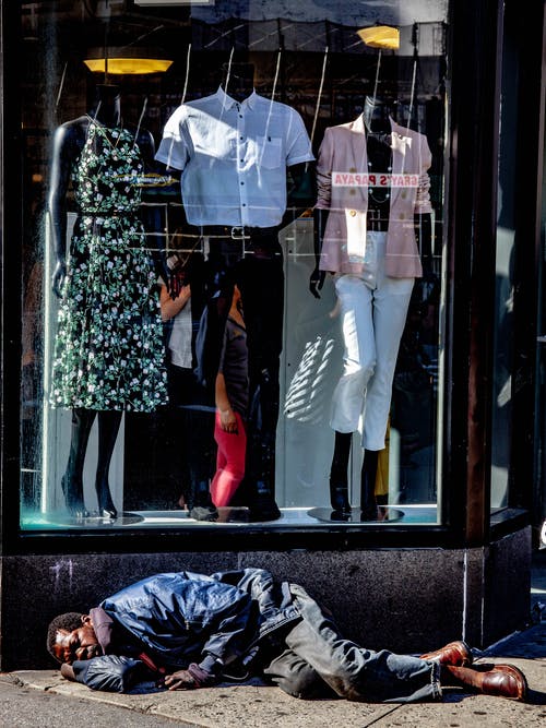 无家可归的人在服装店前睡觉的照片 · 免费素材图片