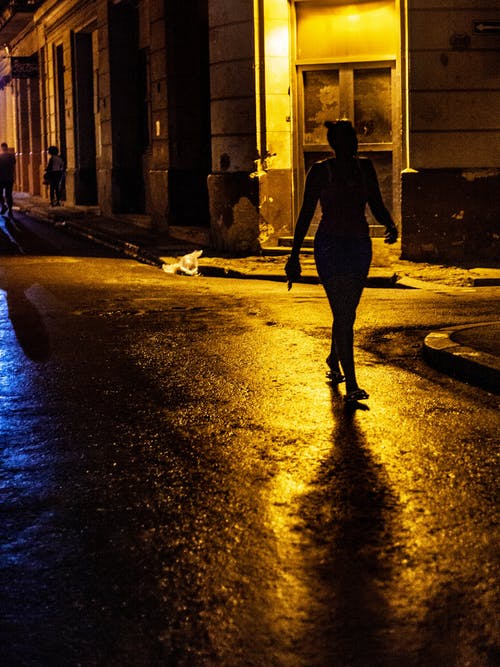 女人在夜间走在路上的剪影照片 · 免费素材图片