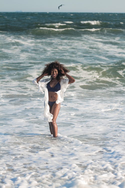 海滩摆在比基尼泳装的微笑妇女的照片 · 免费素材图片