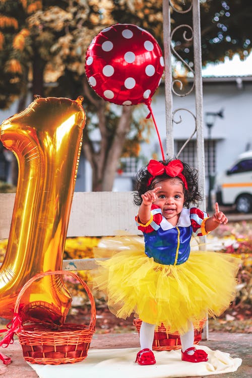 站在大金号1气球旁边的芭蕾舞短裙礼服的女婴的照片 · 免费素材图片