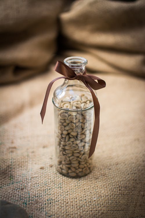 棕色玻璃上的透明玻璃瓶中的咖啡豆 · 免费素材图片