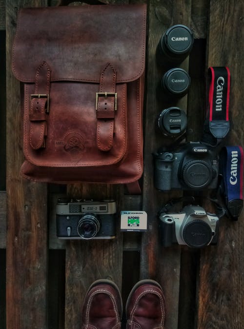 棕色皮包旁边的三个数码单反相机 · 免费素材图片