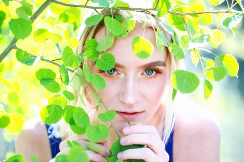 隐藏在绿树上的蓝色背心的女人 · 免费素材图片