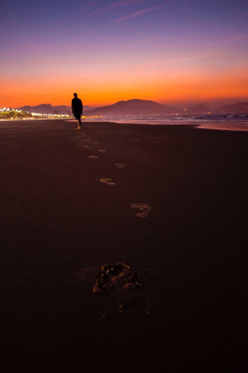 人走在海滩旁边的剪影摄影 · 免费素材图片