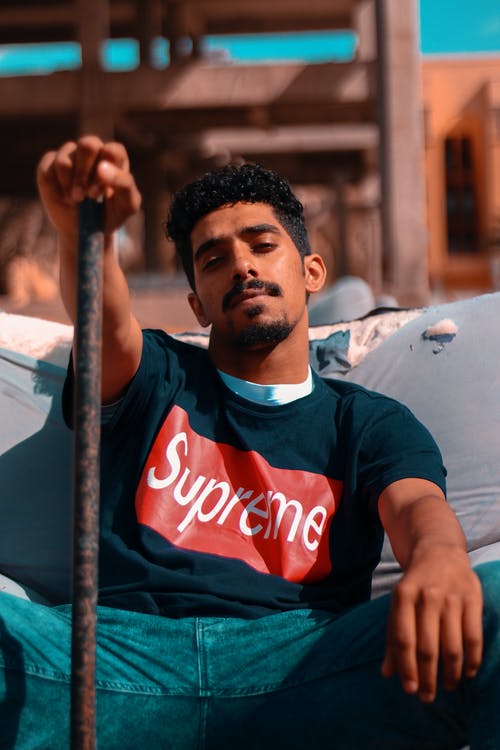 男子坐在沙发上抱着棕色金属棒 · 免费素材图片