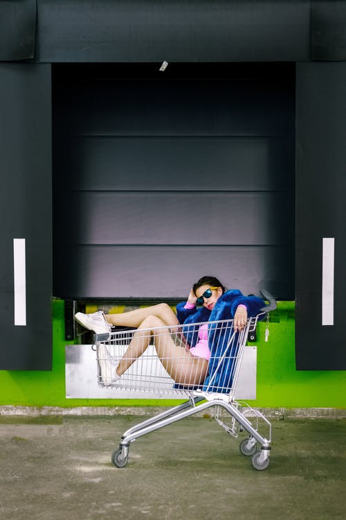 女人坐在购物车摆姿势的照片 · 免费素材图片