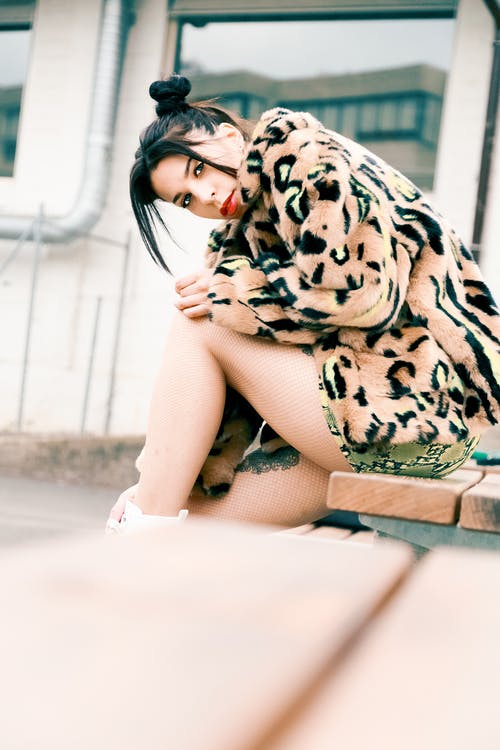 女人穿着皮大衣，坐在棕色的木凳上的摄影 · 免费素材图片