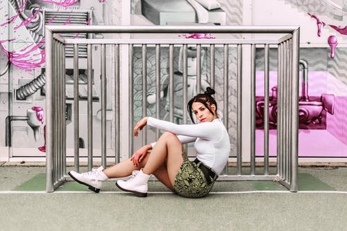 女人坐在旁边的灰色金属轨 · 免费素材图片