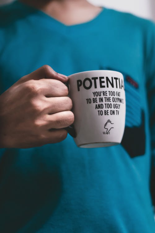 蓝绿色衬衫拿着白色陶瓷杯的人 · 免费素材图片