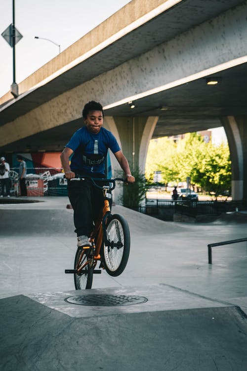 穿蓝衬衫骑自行车在舷梯上的男孩 · 免费素材图片