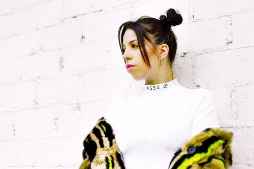 穿白色上衣，倚在白墙上的女人 · 免费素材图片