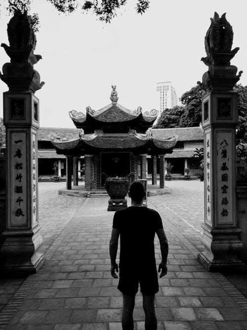 人站在寺庙附近的灰度照片 · 免费素材图片