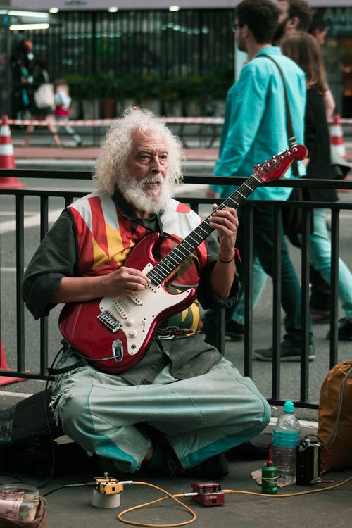 男人玩红色和白色的电吉他 · 免费素材图片