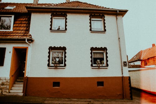 棕色和白色建筑上的两个打开的窗口 · 免费素材图片