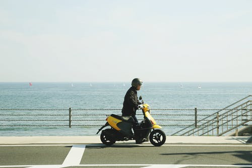 男子骑黄色摩托车在路上 · 免费素材图片