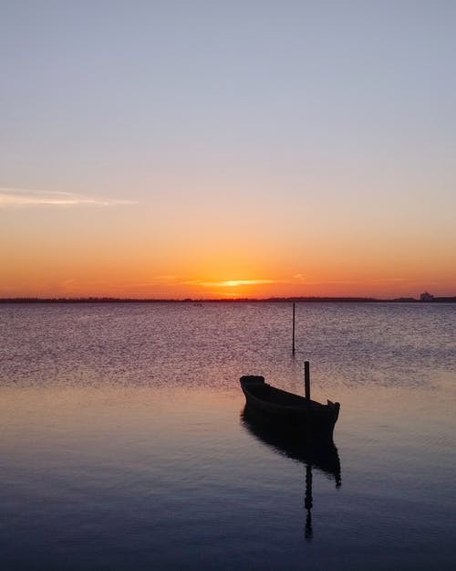 在日落期间在水上划船 · 免费素材图片