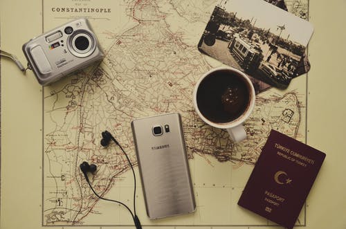 杯黑咖啡附近的银色相机，三星银河s7，土耳其护照和黑色耳塞 · 免费素材图片