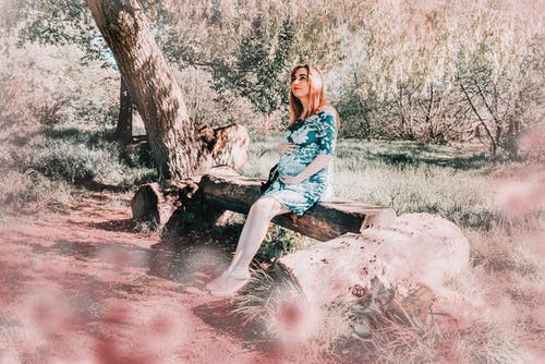 孕妇在绿色和白色的花裙子，坐在板凳上 · 免费素材图片