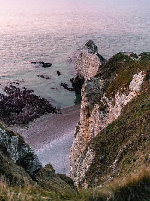 面对海滩的棕色岩石地层 · 免费素材图片