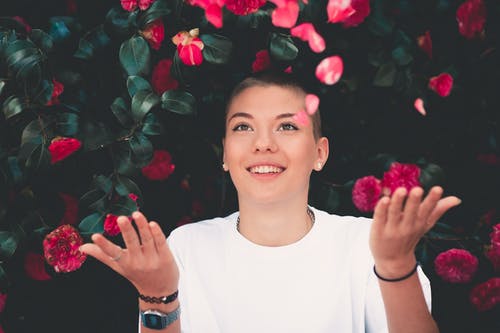玩粉红色花朵的白色圆领衬衫的女人 · 免费素材图片