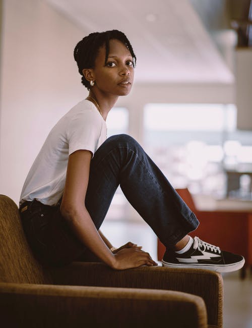 女人坐在沙发上，穿着白色的t恤 · 免费素材图片