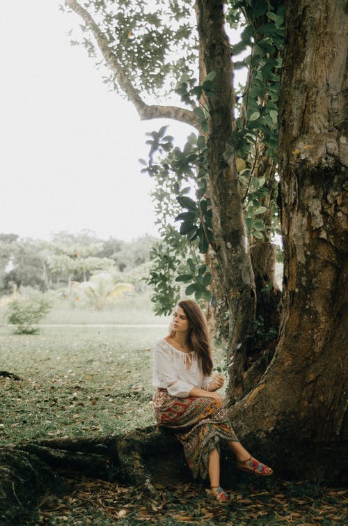 坐在一棵树下的女人的照片 · 免费素材图片