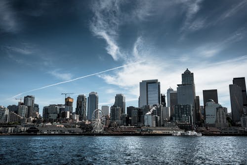 穿过城市建筑物的白色摩天轮照片 · 免费素材图片
