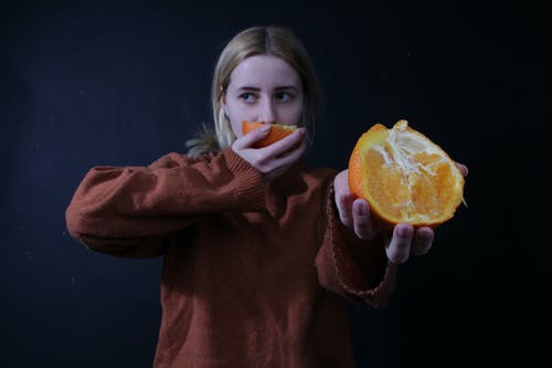 女人抱着橙色柑橘类水果 · 免费素材图片