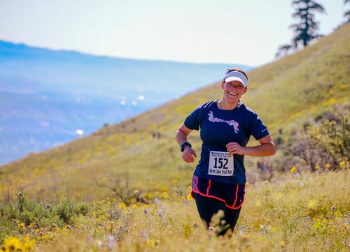 慢跑在绿草覆盖的山坡上的女人 · 免费素材图片