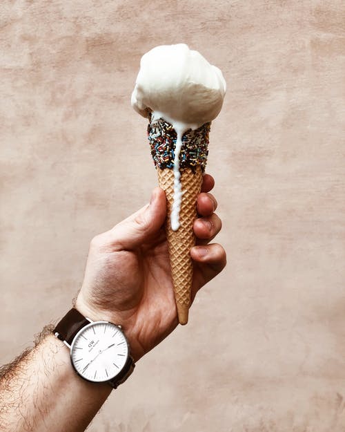 该名男子手持融化的冰淇淋蛋卷的特写照片 · 免费素材图片