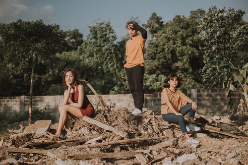 三人在一堆废料上的照片 · 免费素材图片