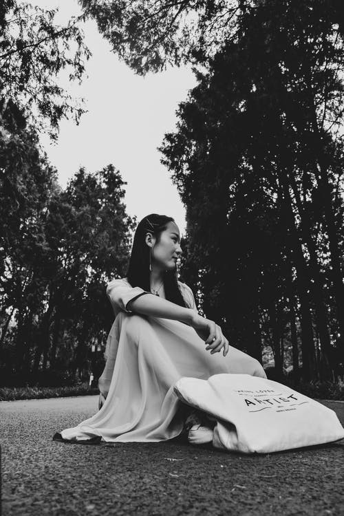 女人坐在沥青上的灰度照片 · 免费素材图片