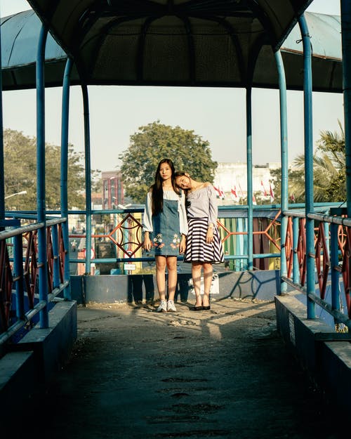 站在蓝色钢轨旁边的两个女孩 · 免费素材图片