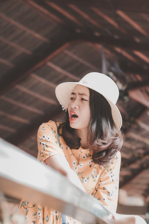 惊讶的女人在太阳帽和花裙子回望的照片 · 免费素材图片