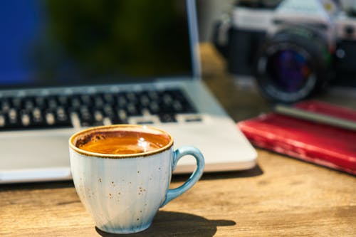 一杯咖啡和一台照相机在工作场所的木桌上 · 免费素材图片