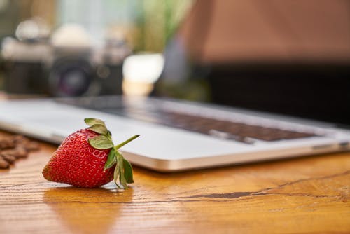 草莓在笔记本电脑附近的特写照片 · 免费素材图片