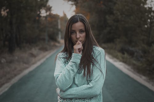 站在树中间的道路中间的女人的照片 · 免费素材图片