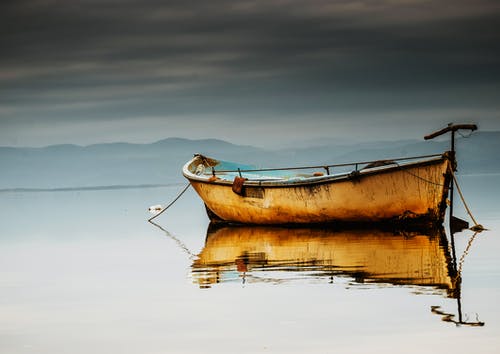 平静的水体上的棕色独木舟 · 免费素材图片