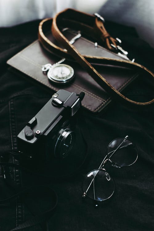 相机袋和眼镜旁边的黑色相机 · 免费素材图片