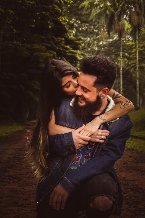 女人回拥抱和亲吻男人在森林里 · 免费素材图片
