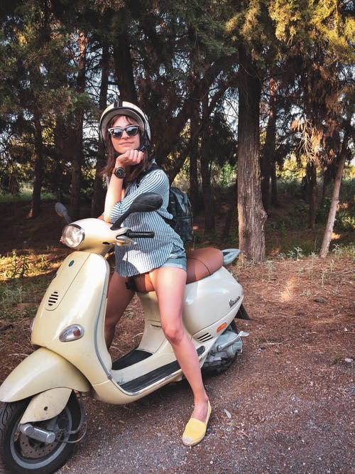 女人在米色的小型摩托车上戴头盔 · 免费素材图片