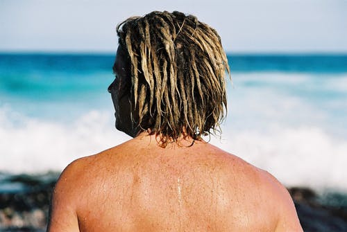 戴着金色长发lock站在海边的人的照片 · 免费素材图片