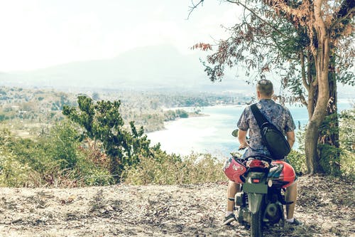 男子骑摩托车在树附近 · 免费素材图片