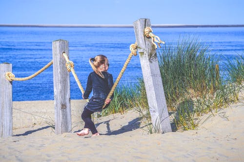 女孩坐在沙子上的栅栏上的绳索 · 免费素材图片