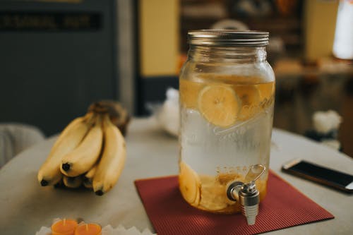 桌上的透明玻璃饮料分配器和香蕉 · 免费素材图片